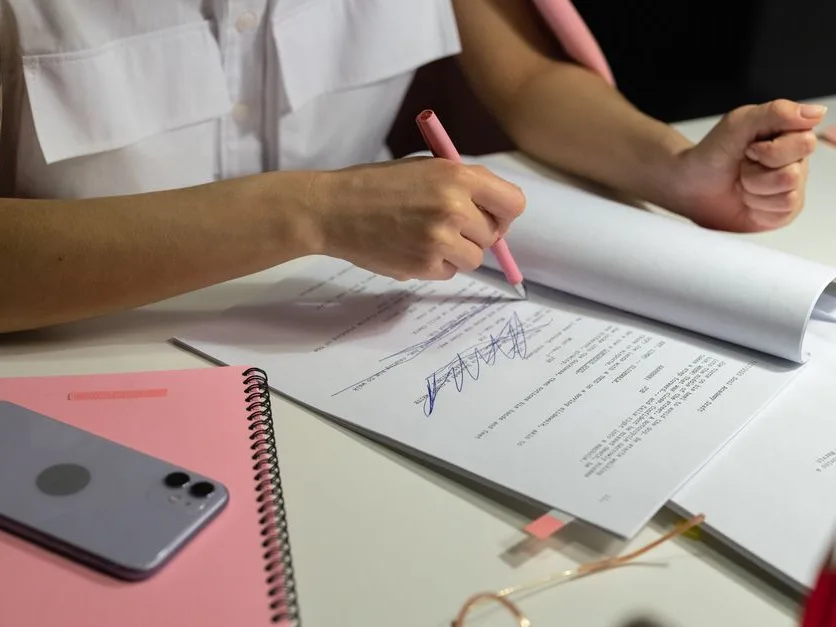 Mains qui annotent des documents imprimés au stylo sur un bureau